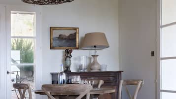Un coin repas rustique avec une table en bois, des chaises, une lampe et un tableau accroché au mur.
