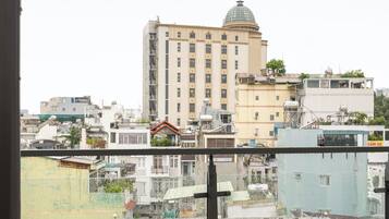 Uma varanda com mesa e cadeiras, com vista para um horizonte urbano com diversos edifícios, incluindo um prédio imponente com cúpula.