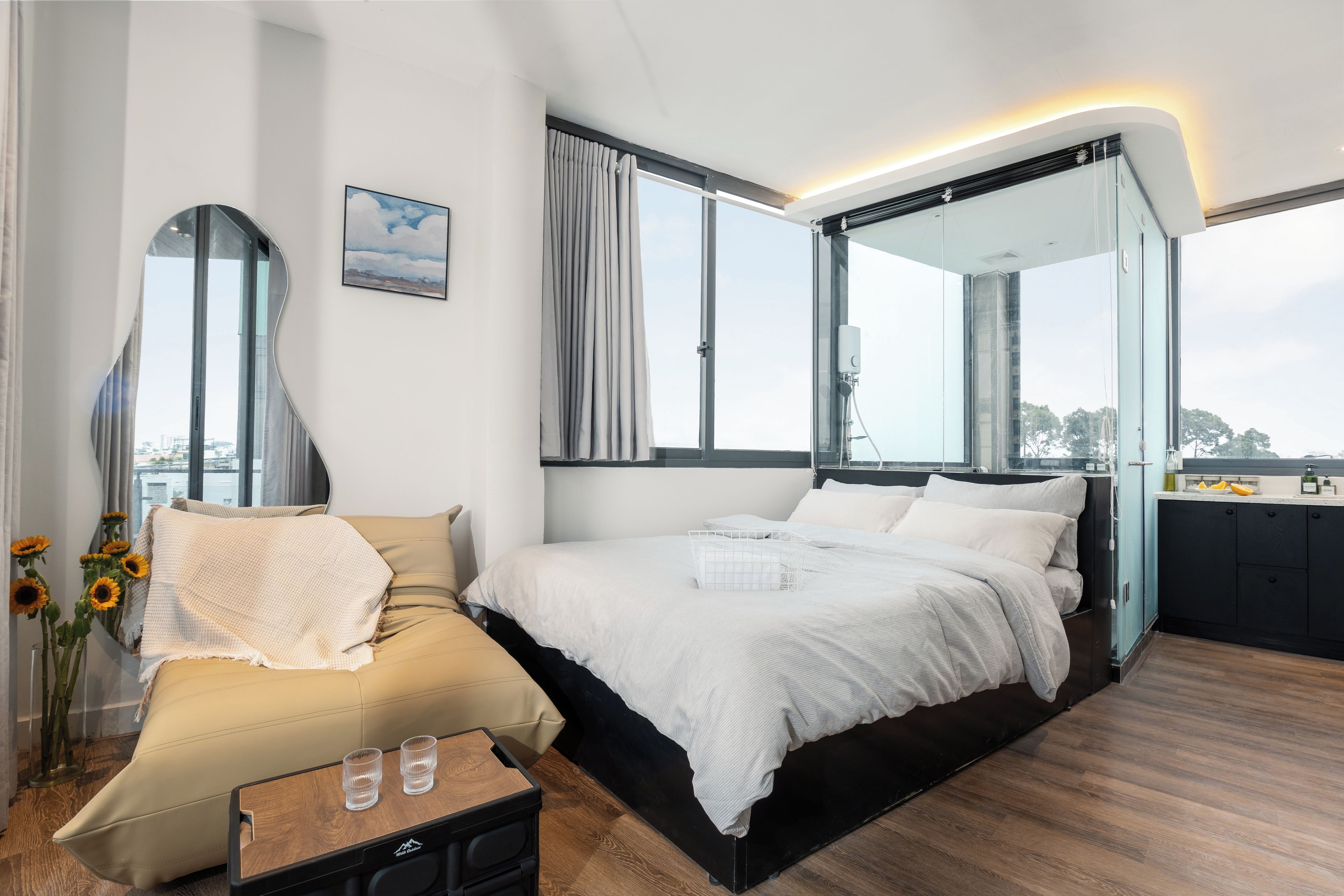 Une chambre moderne avec un grand lit, un canapé, une cloison en verre et une vue sur la ville.