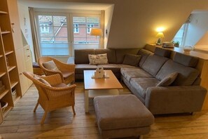 En hyggelig stue med sofa, to lænestole, et sofabord og en bogreol.