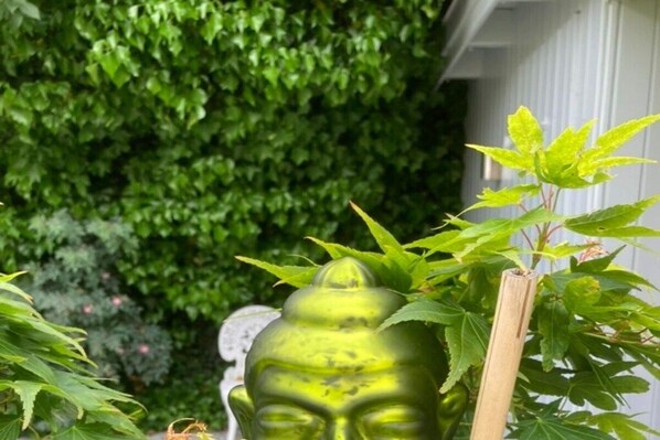 Una estatua verde de Buda rodeada de follaje.