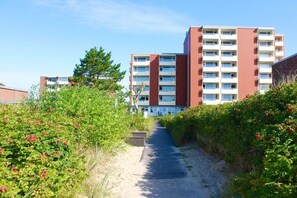 A pathway leading to a multi-story residential building with a brick facade and multiple balconies. - 16 in the Uthlande house (Wyk auf Föhr)