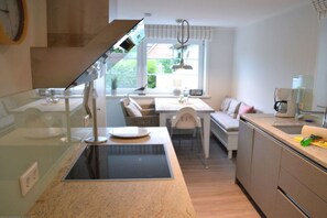 Une cuisine moderne dotée d’une cuisinière intégrée, un coin repas avec une table et des chaises, et une fenêtre donnant sur un paysage verdoyant.