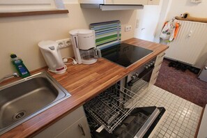 Une cuisine compacte équipée d’un lave-vaisselle, d’une machine à café et d’un four à micro-ondes.
