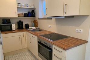 Eine kompakte Küche mit Mikrowelle, Kaffeemaschine, Wasserkocher und Backofen.