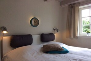 A bedroom with a bed, two wall-mounted clocks, and a window with curtains. - Holiday home in Oldsum with swimming pool (Oldsum)
