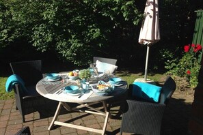 An outdoor dining area with a round table, chairs, and a table umbrella. - Holiday home in Oldsum with swimming pool (Oldsum)