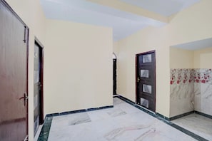 Um corredor com piso de mármore, porta de madeira e parede com padrão floral.