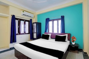 A hotel room with a bed, a nightstand, a vase with flowers, and a window with curtains. - Hotel O Chitrakut Nagar Royal Brothers (Danapur)