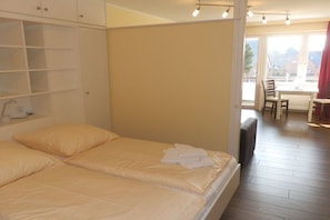 A hotel room with a bed, a small table, and a view of the outside. - Holiday apartment with 1 bedroom (Wyk auf Föhr)