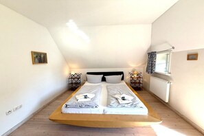 A bedroom with a single bed, two bedside tables, a window with curtains, and a radiator. - Holiday home in Oldsum with swimming pool (Oldsum)