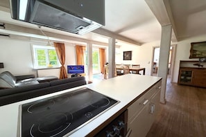 A modern kitchen with a built-in stove, dining area with chairs, and a view of the outdoors. - Holiday home in Oldsum with swimming pool (Oldsum)