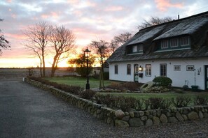 A traditional white building with a thatched roof, a stone wall, and a gravel driveway. - 3 in the Deichhof house (Dunsum)