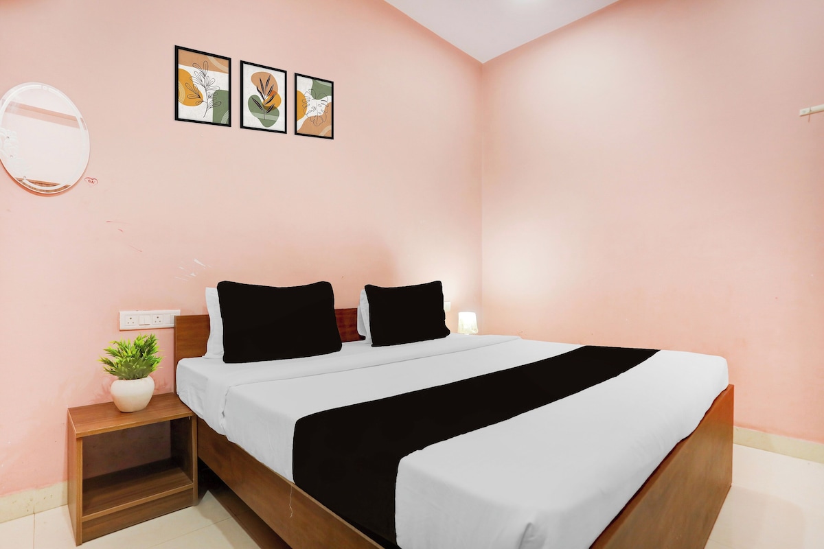 A bedroom with a bed, a nightstand with a plant, and three framed pictures on the wall.