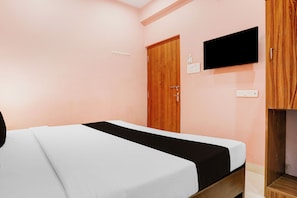 A bedroom with a bed, a wooden wardrobe, a television mounted on the wall, and a door. - Hotel O IIT Varanasi Shree Gopal Upwan  (Varanasi)