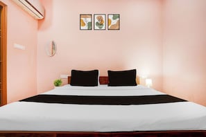 A bedroom with a bed, two black pillows, a bedside table with a lamp, and three framed artworks on the wall. - Hotel O IIT Varanasi Shree Gopal Upwan  (Varanasi)