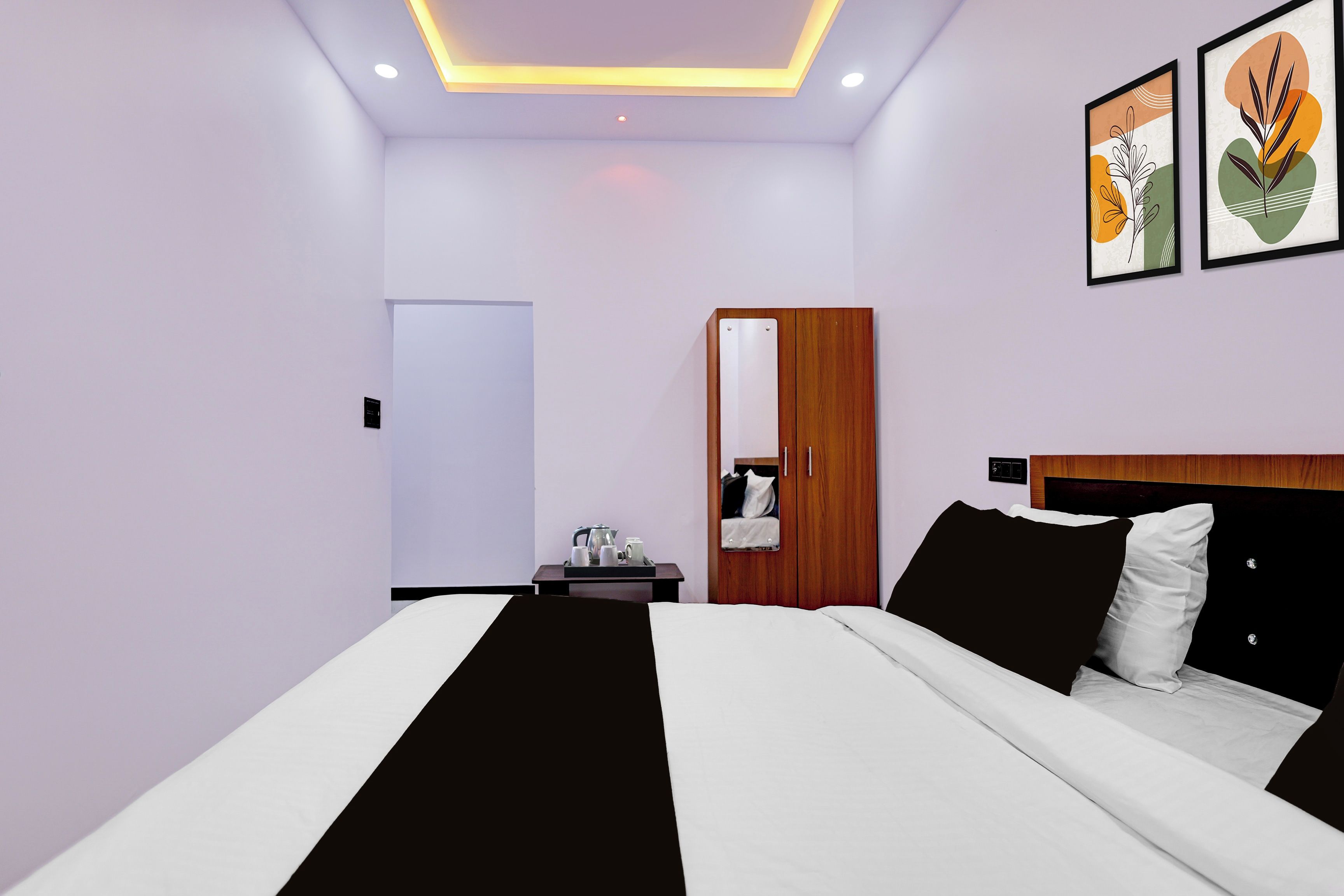 A modern hotel room with a bed, bedside table, and a mirror.