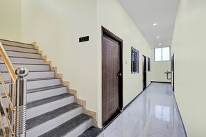 A clean, modern hallway with a marble floor, a wooden door, and a staircase with a metal handrail. - Super Hotel O AIIMS Nagpur (Nagpur)