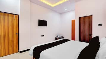A hotel room with a bed, a desk, a TV, and a wardrobe.