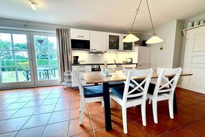 Eine moderne Küche mit weißen Schränken, einem Holztisch und Stühlen.