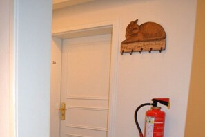 A white door with the number 28, a wooden cat decoration, and a red fire extinguisher mounted on the wall. - 28 in the Deichhof house (Dunsum)