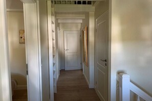 A narrow hallway with a wooden floor, white walls, and a white door at the end. - 5 in the Deichhof house (Dunsum)