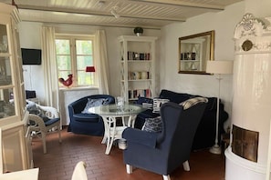 A living room with a fireplace, a bookshelf, and a dining table. - Holiday home at the spa park 1a (Wyk auf Föhr)