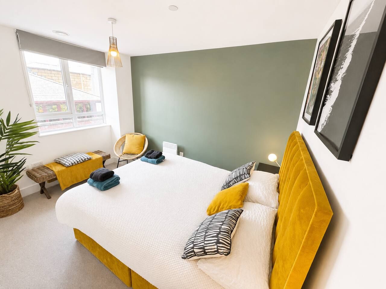 A bedroom with a bed, bedside tables, a chair, a potted plant, and a window.