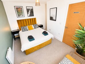 A bedroom with a bed, a bedside table, a lamp, a plant, and a door with a 'NO ENTRY' sign. - Free Parking | Stokes Croft 2-Bed Flat | Sleeps 5 (Saint Paul's)
