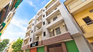 Un edificio de hotel con varios pisos, balcones, unidades de aire acondicionado y un letrero que indica que es administrado por OYO.