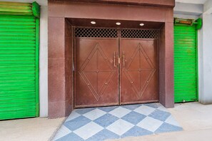A double door with geometric patterns, flanked by green shutters, and a tiled entrance area. - Hotel O Patliputra Golmber Patna Suncity (Patna)