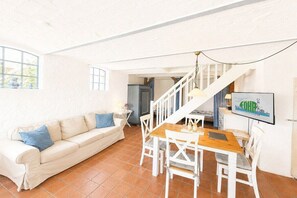 A living room with a sofa, a dining table with chairs, a staircase, and a television. - Holiday apartment in Oevenum with Wi-Fi (Oevenum)