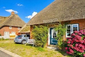 A traditional thatched-roof house with a brick exterior, a bench, and a car parked in front. - Holiday apartment in Oevenum with Wi-Fi (Oevenum)