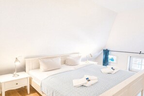 A bedroom with a bed, nightstands, and a window with curtains. - Holiday apartment in Oevenum with Wi-Fi (Oevenum)