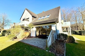 Et moderne hus med skråt tag, store vinduer og en velholdt have.