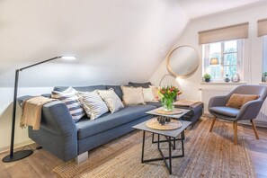 Un salon moderne avec un canapé, un fauteuil, une table basse, un lampadaire et un miroir au mur.
