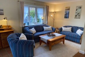 A living room with striped sofas, a wooden coffee table, and a lamp. - 8b in the building on Neuer Weg (Wrixum)