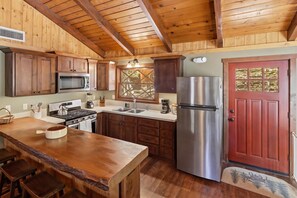 Une cuisine dotée de meubles en bois, d’un réfrigérateur en acier inoxydable et d’un îlot central en bois avec des tabourets.