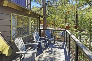 A wooden deck with Adirondack chairs, a railing, and a view of a forested area. - PET FRIENDLY! Fenced Yard! Game Room! Flat Driveway! (Big Bear Lake)
