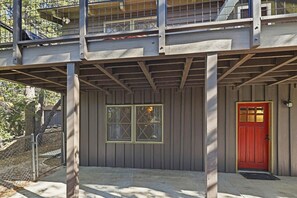A building with a red door, a covered porch area, and a fenced entrance. - PET FRIENDLY! Fenced Yard! Game Room! Flat Driveway! (Big Bear Lake)