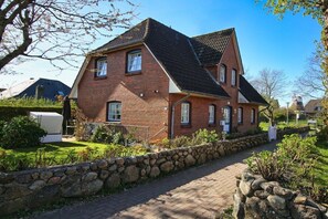 A two-story brick house with a stone wall and a paved driveway. - Holiday home in Wrixum with terrace (Wrixum)