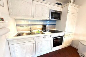A kitchen with white cabinetry, a microwave, an oven, and a sink. - Holiday home in Wrixum with terrace (Wrixum)