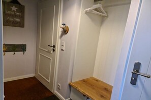 Ein Badezimmer mit einer weißen Tür, einem hölzernen Regal und einem Handtuchhalter.
