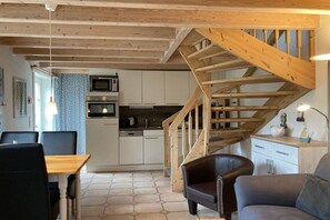 Eine moderne Küche mit weißen Schränken, einer Holztreppe und einem Essbereich mit Tisch und Stühlen.