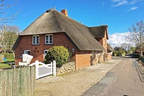 A traditional brick house with a thatched roof, a white picket fence, and a gravel driveway. - Holiday apartment in Wrixum with terrace (Wrixum)