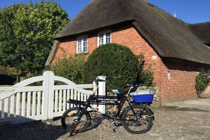 Ein Haus mit einem Strohdach, vor dem ein Fahrrad steht.