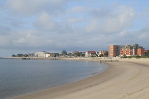 A beach with a pier, buildings, and a clear sky. - Haus Hansen Wyk - Holiday Apartment 01 (Wyk)