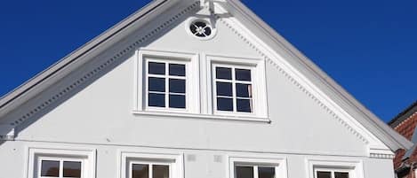 A white building with a triangular roof and a clock on the facade.