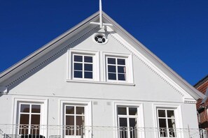 Ein weißes Gebäude mit einem dreieckigen Dach und einer Uhr an der Fassade.
