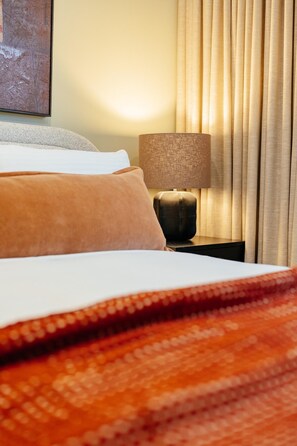 A neatly made bed with a patterned blanket, a bedside lamp, and a window with curtains. - StayCentral - The Marque II - The Marque II - 2 Bedrooms, 2 Beds, 1 Bathroom, 2 Car Park (Collingwood)